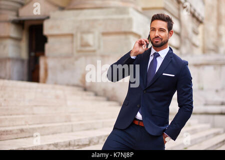 A handsome young businessman standing on the stairs while talking his phone Stock Photo