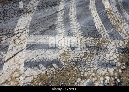 Muddy tyre tracks on cracked road surface from farm vehicles - France. Stock Photo