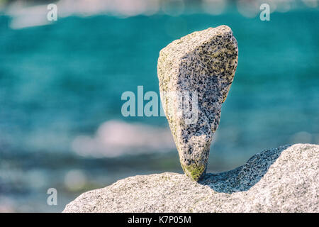 Triangular rock balanced on the tip in Vancouver rock stacking garden Stock Photo