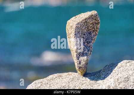 Triangular rock balanced on the tip in Vancouver rock stacking garden Stock Photo