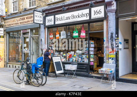 Woman browsing in the window of the Brick Lane Bookshop in Whitechapel. Stock Photo