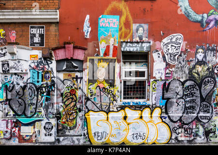Wall covered with overlaying palimpsest of paste up graffiti and tags. Stock Photo
