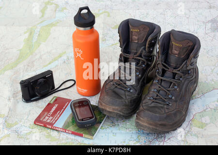 Preparing to walk the Cumbria Way. Hiking boots, water bottle, camera, handheld GPS unit and guidebook on an Ordnance Survey map of the Lake District Stock Photo