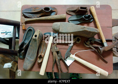 A display of antique shoemaker's or cobbler's tools on a table Stock Photo