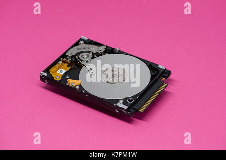 Close-up of an opened computer hard drive disk on mauve colored background. Stock Photo