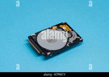 Close-up of an opened computer hard drive disk on blue colored background. Read-write head retracted. Stock Photo