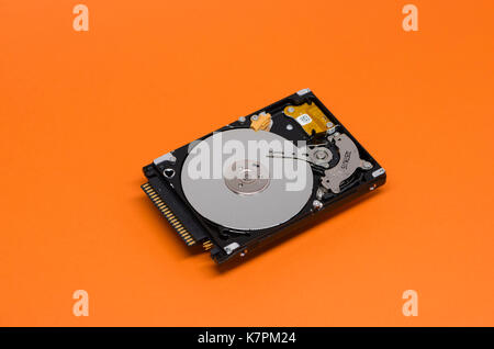 Close-up of an opened computer hard drive disk on orange colored background. Stock Photo