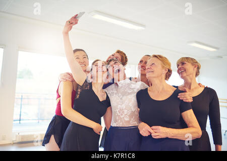 Laughing group of women standing arm in arm together and making faces while taking selfies in a dance studio Stock Photo