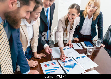 Multi-ethnic team of five dedicated specialists smiling while an Stock Photo