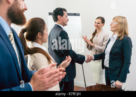 Two middle-aged business associates smiling while shaking hands  Stock Photo