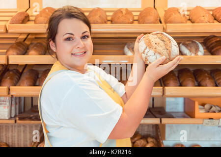 Saleslady in bakery shop presenting bread  Stock Photo