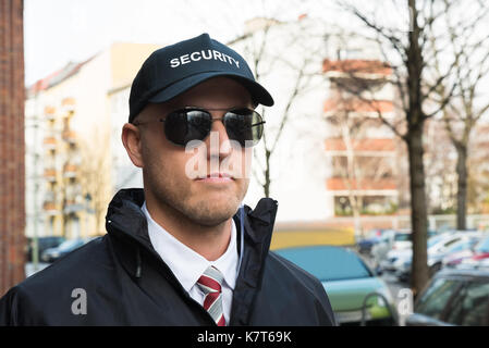 Portrait Of Young Security Guard Wearing Black Uniform And Glasses Stock Photo