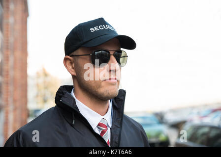 Portrait Of Young Security Guard Wearing Black Uniform And Glasses Stock Photo