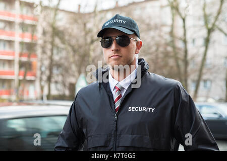 Portrait Of Young Security Guard Wearing Black Uniform And Glasses Stock Photo