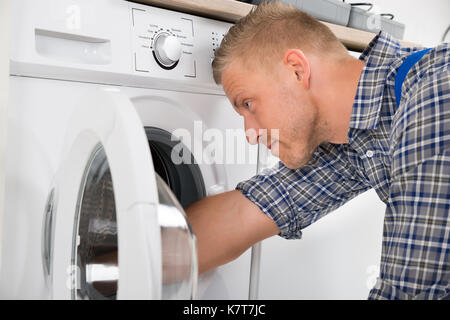 Close-up Of Professional Handyman In Overall Repairing Washing Machine Stock Photo