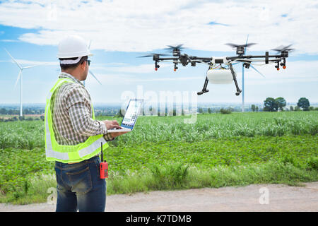 Technician farmer use wifi computer control agriculture drone on sugarcane field Stock Photo
