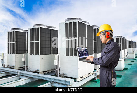 Electrical engineer using laptop computer for maintenance air conditioning system on rooftop of factory Stock Photo