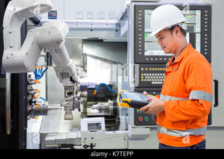 Maintenance engineer programing automated robotic with CNC machine in an industry Stock Photo