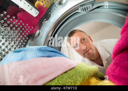 Close-up Of Man View From Inside The Washing Machine With Multi-colored Clothes Stock Photo