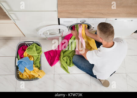 High Angle View Of Young Man Using Washing Machine Appliance At Home Stock Photo