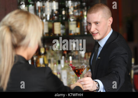 Barman serving cocktail to customer in Hotel bar Stock Photo