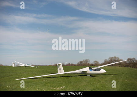 Two gliders on the ground with a third glider being towed in the air by a tow plane. Storrington, West Sussex, United Kingdom Stock Photo