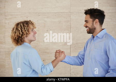 Profile portrait of two happy businessmen shaking hands Stock Photo