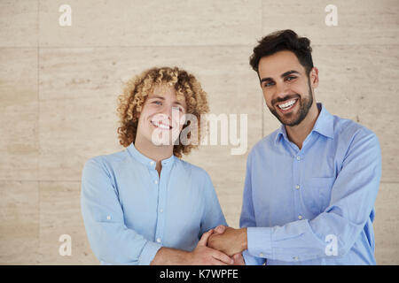 Front portrait of young businessmen shaking hands smiling Stock Photo