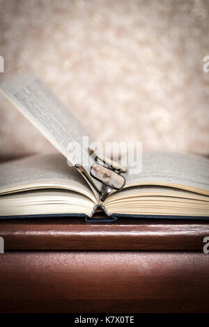 Book and glasses lying on the dresser closeup. Stock Photo