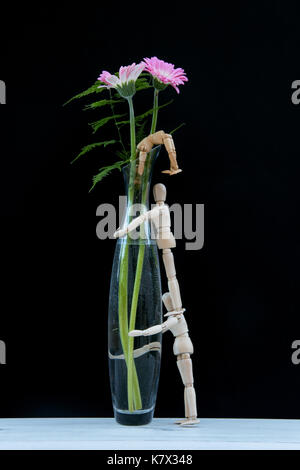 Three mannequins climbing  tall vase, the one at the top has fallen in Stock Photo