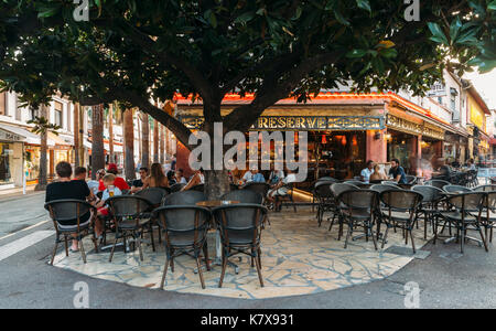 Holidaymakers in Juan les Pins, Cote d'Azur, France sit at a terrace in a restaurant during the summer Stock Photo