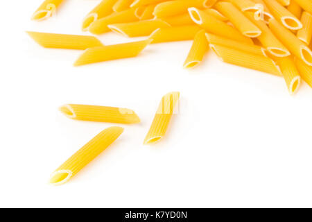 Closeup of raw, uncooked, dry penne pasta noodles with selective focus on white background Stock Photo