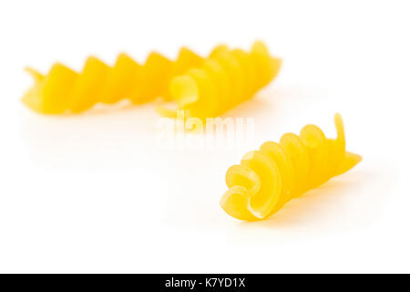 Closeup of raw, uncooked, dry fusilli or rotini pasta noodles with selective focus on white background Stock Photo