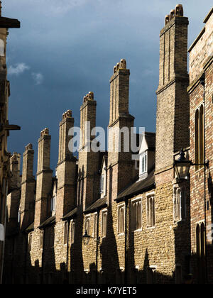 Before the Storm: Identical, Old Cambridge Chimneys Stand in Bright Sunshine as Dark Clouds Approach Stock Photo