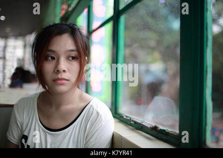 Sad woman waiting someone who is late, after cry,she look outside nearby window,  reflection on glasses in restaurant of Hong Kong Stock Photo