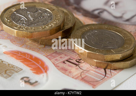 Image of the new, plastic, ten pound, sterling, note with five one pound sterling coins on top of it. Stock Photo