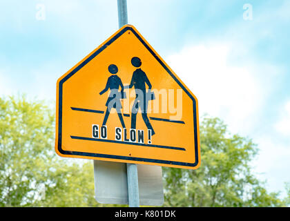 School crossing sign with blue sky and go slow lettering Stock Photo