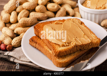 Peanut butter sandwich on plate with inshell peanuts, breakfast on the wooden background Stock Photo