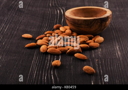 Almonds in brown bowl on wooden background Stock Photo