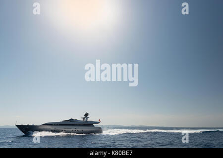 Fast luxurious motor yacht on open sea with sun in background Stock Photo