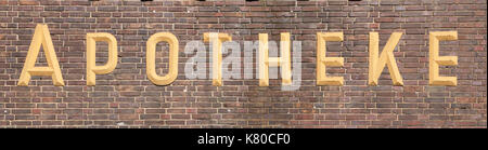 chemist's shop sign on a brown brick wall Stock Photo