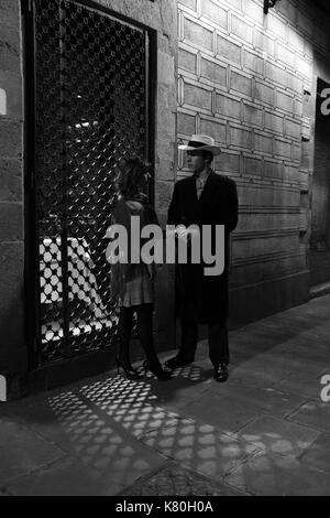 Black and white film noir image of man and woman in lamplight Stock Photo