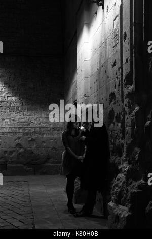 Black and white film noir image of man and woman in lamplight Stock Photo