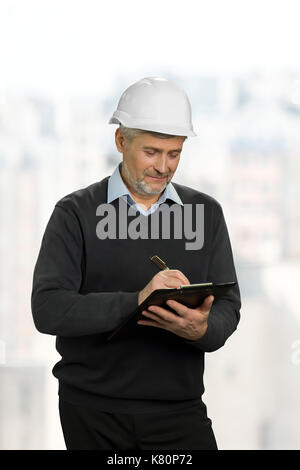Mature foreman writing on clipboard. Stock Photo