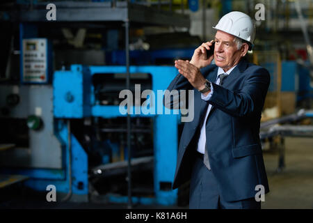 Busy Senior Entrepreneur Using Smartphone Stock Photo