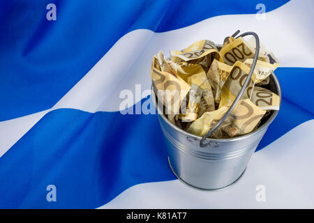 Greek flag with a metal bucket of 200 Euro banknotes. For Greek financial crisis & bailout, Greek debt relief, Greece economic slump, Greek recession. Stock Photo
