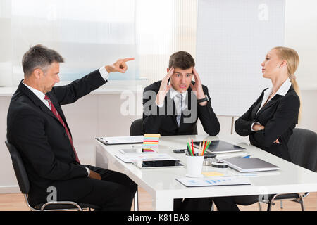 Mature Businessman Arguing With His Two Co-workers In Office Stock Photo