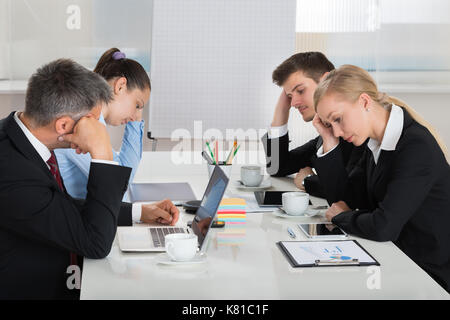 Team Of Unhappy Businesspeople Sitting In Business Meeting Stock Photo