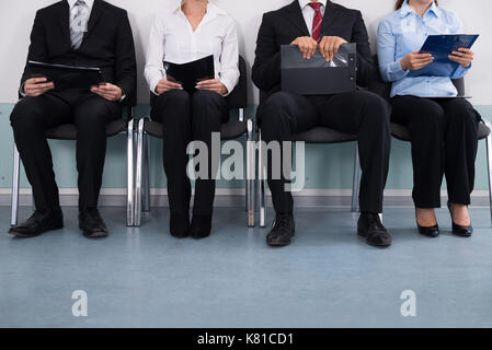Close-up Of Businesspeople With Files Sitting On Chair Stock Photo