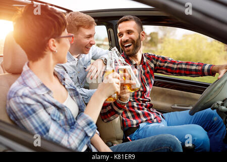 Group of smiling friends having fun in the car on road trip Stock Photo